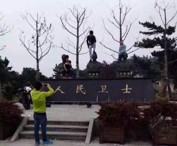 国庆期间，杭州萧山区，3名年轻男子为达到拍照效果，或脚踩或蹲坐在3位消防烈士铜像头顶用以取景。